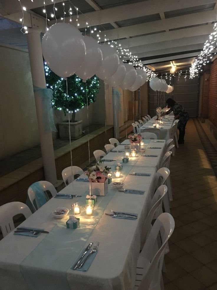 a long table is set up with white balloons and place settings for the dinner guests