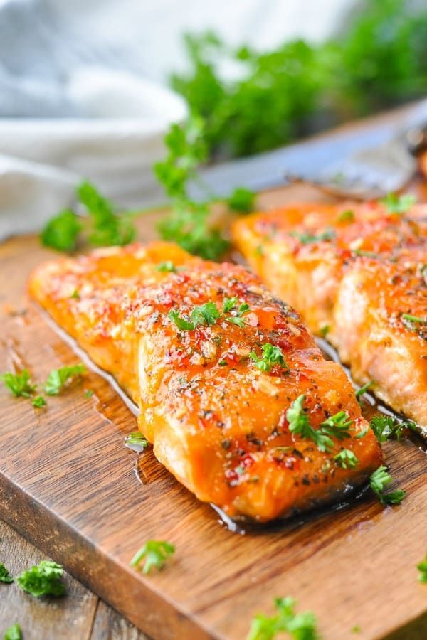 salmon fillets on a wooden cutting board with parsley sprinkled on top