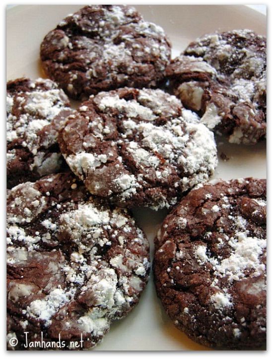 chocolate crinkle cookies with white powdered sugar on top, sitting on a plate