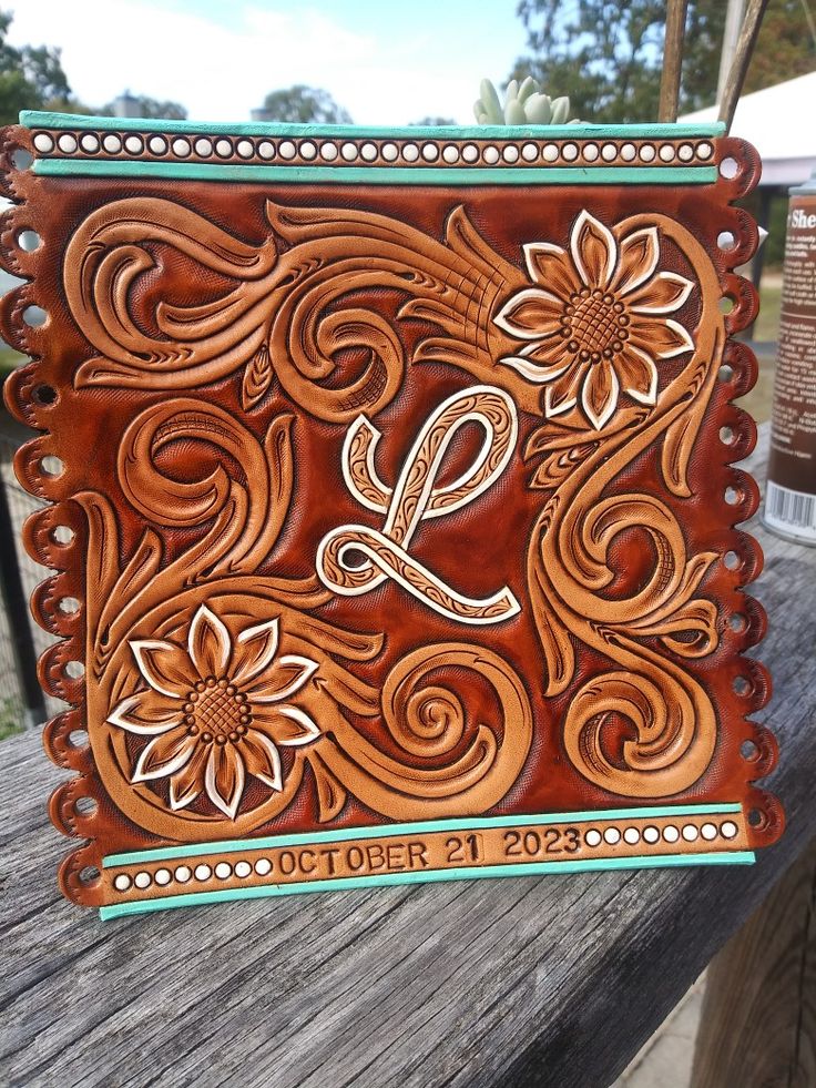 a wooden plaque with the letter l on it sitting on top of a wooden bench