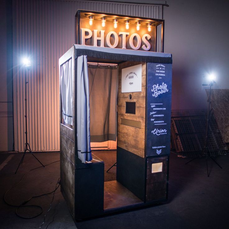 an old fashioned photo booth with lights on the top and bottom floor, in front of a building