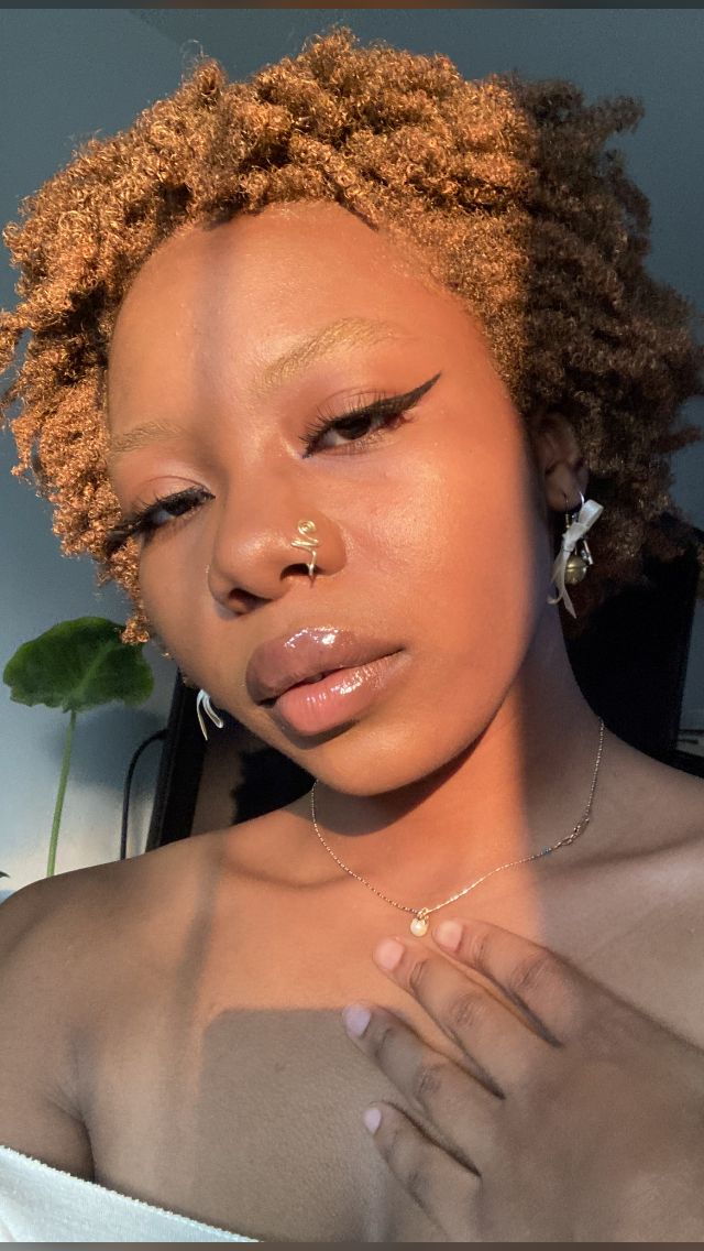 a close up of a woman with her hand on her chest and nose piercings