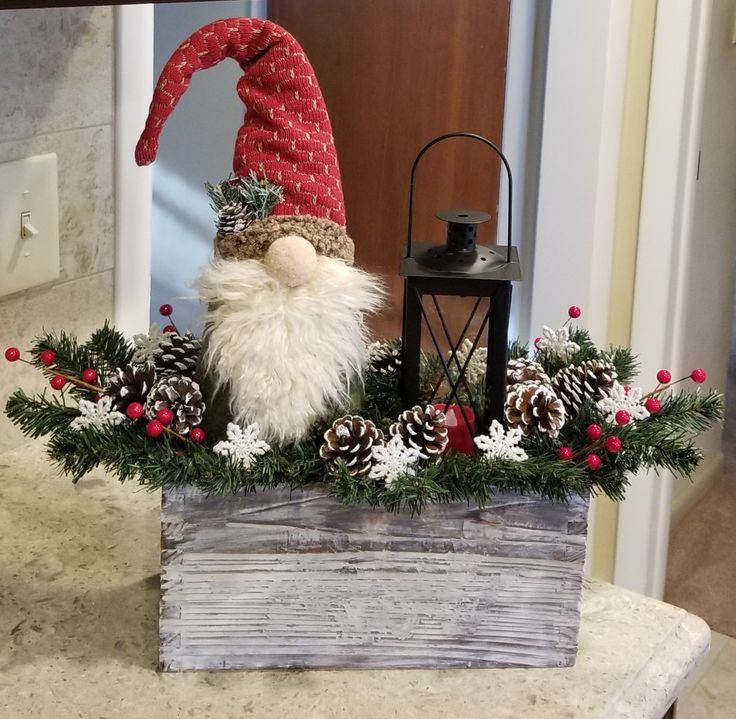 a gnome sitting on top of a wooden box filled with pine cones and evergreens