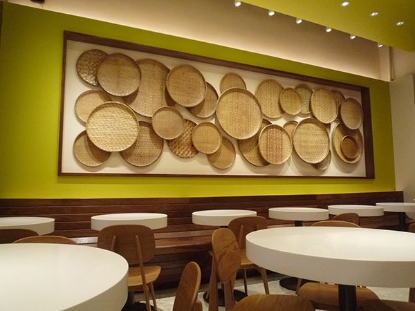 the wall is made out of woven baskets and wooden chairs, along with round tables