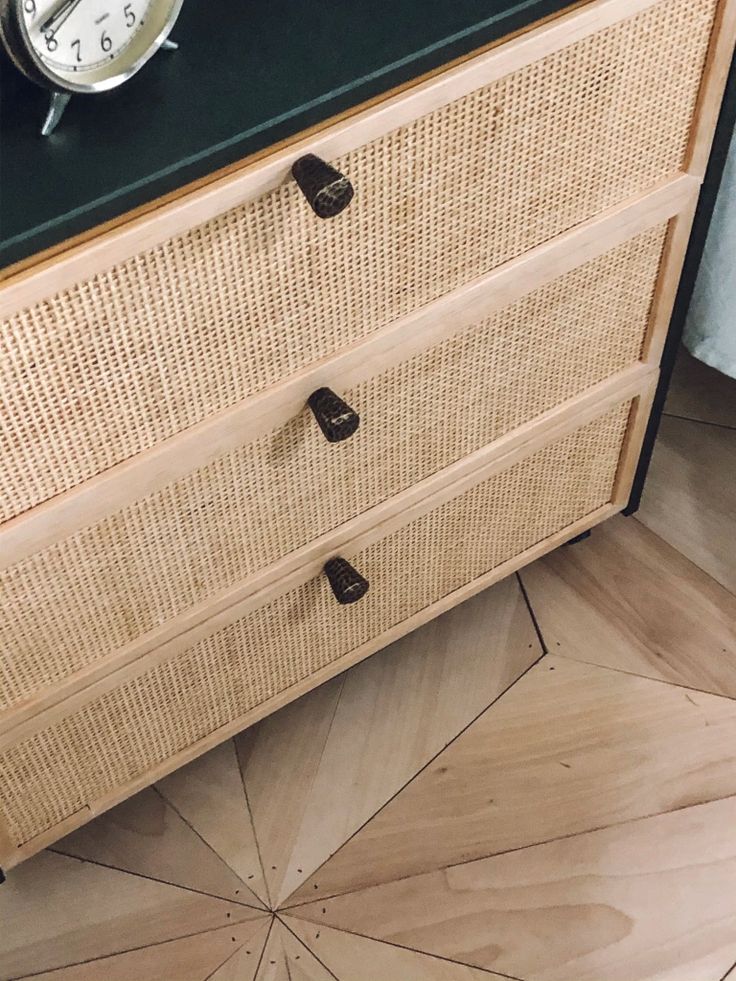 an alarm clock is on top of a wicker dresser with two drawers and one drawer