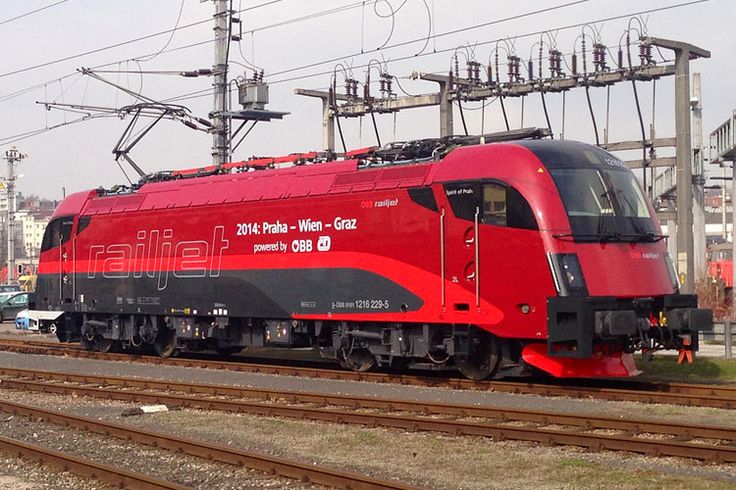 a red train traveling down tracks next to power lines