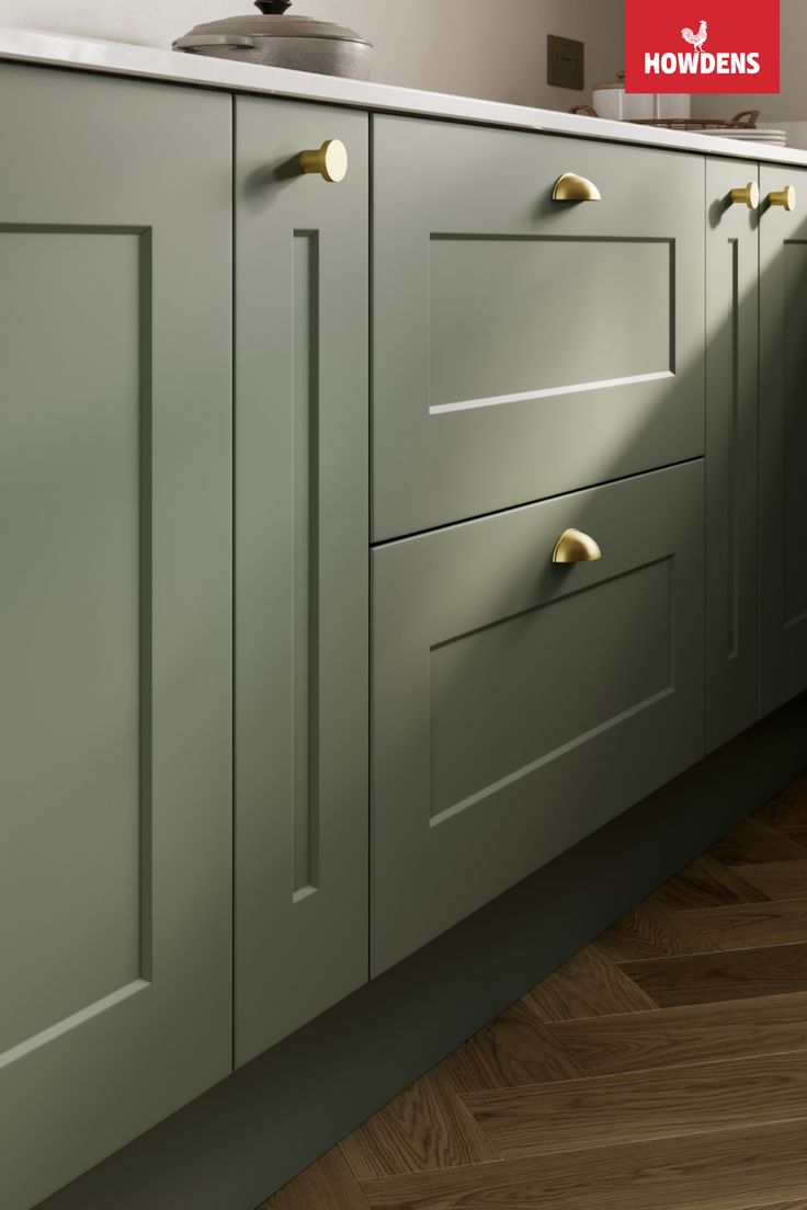 an image of a kitchen setting with green cabinets and wood flooring on the side