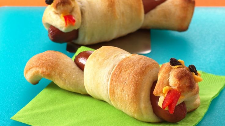 two hotdogs wrapped in bread on top of a green napkin