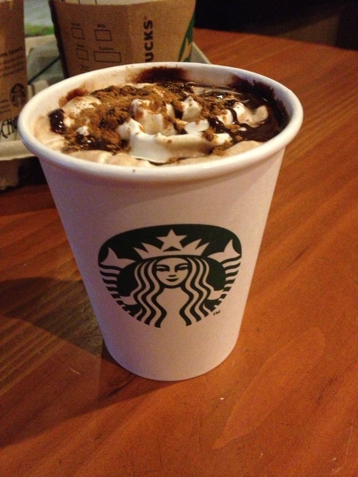 a starbucks drink with whipped cream and toppings on the top is sitting on a table