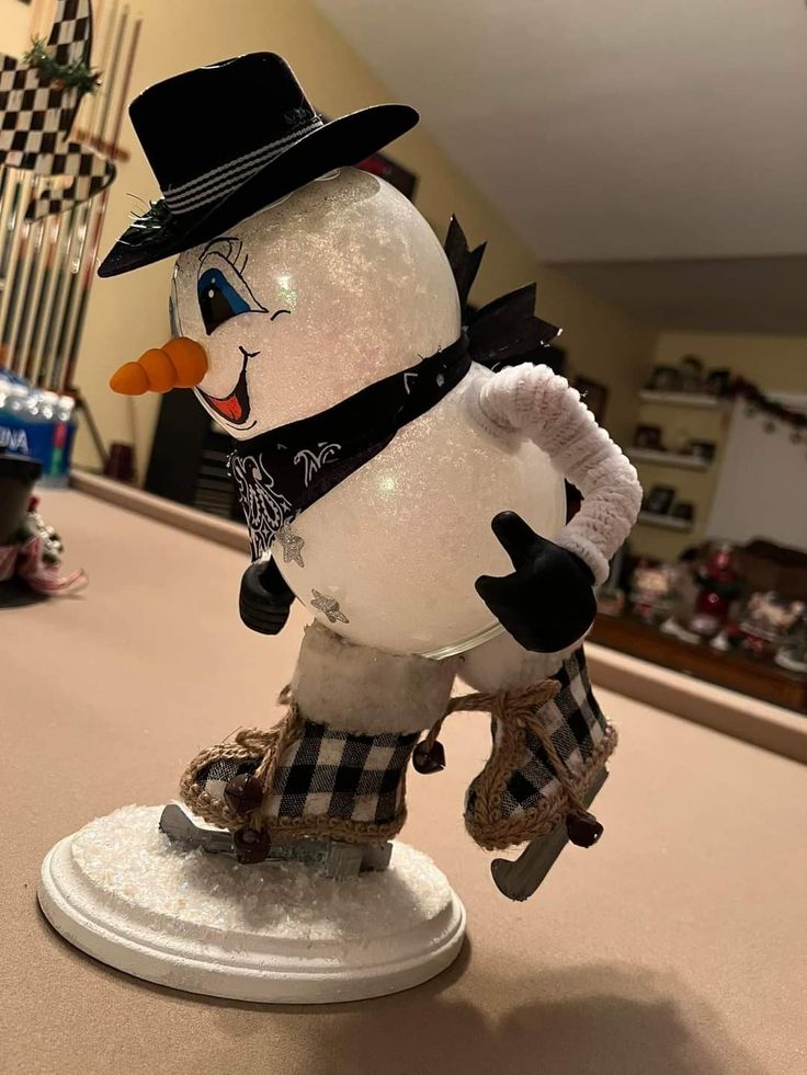 a snowman with a hat and scarf on it's head is standing on a table