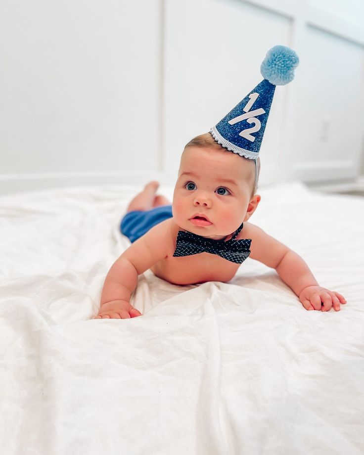 a baby wearing a birthday hat laying on top of a bed