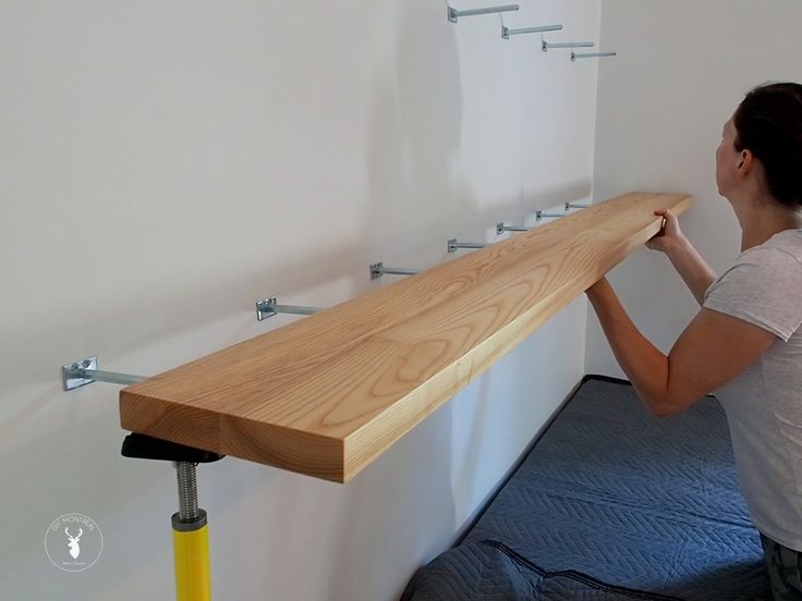 a woman is holding up a wooden shelf