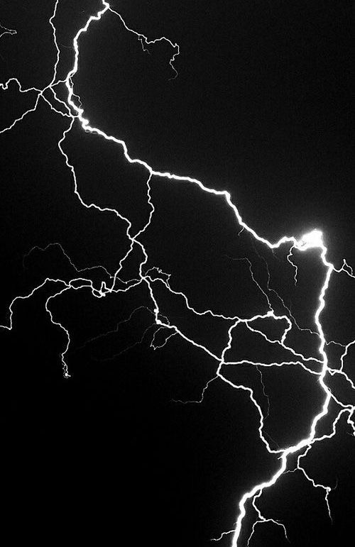 a black and white photo of lightning striking through the night sky, taken from an airplane