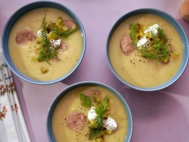 three bowls filled with soup on top of a purple tablecloth next to an orange and white napkin