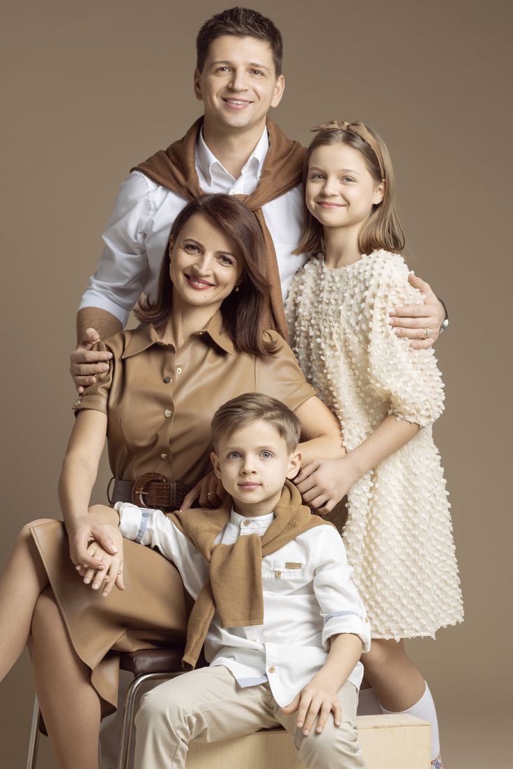 the family is posing for a photo in front of a brown background with their arms around each other