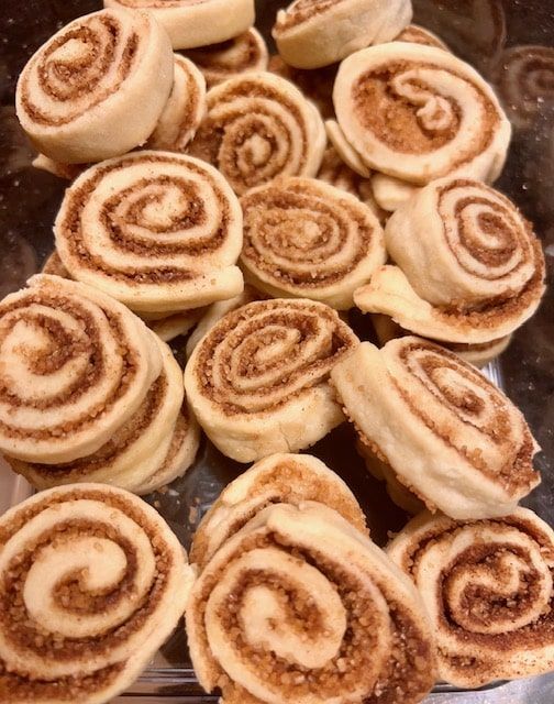 several cinnamon rolls are on a glass platter and ready to be baked in the oven