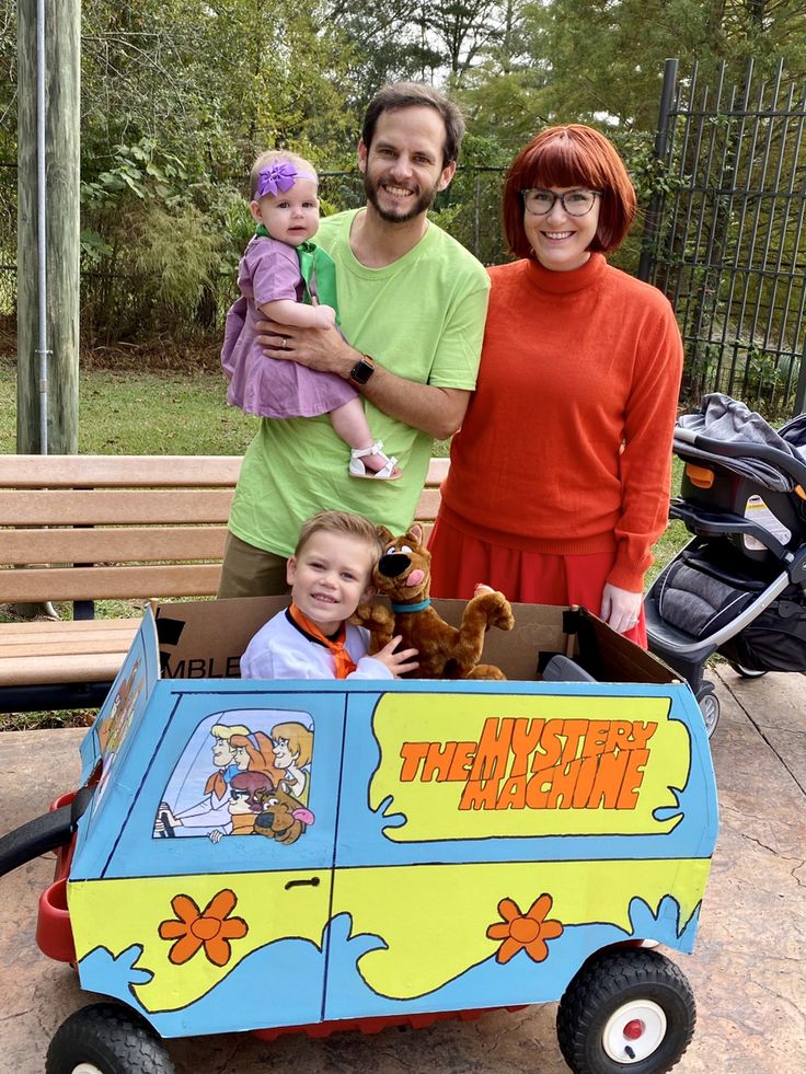 two adults and a child are posing in a toy bus