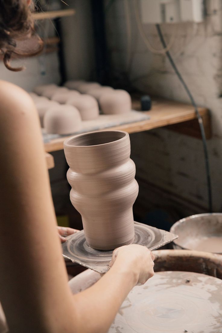 a woman is making pottery on a potter's wheel