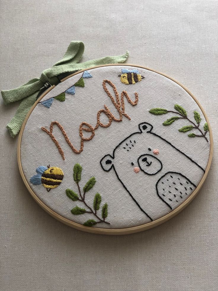 a hand embroidered wall hanging with a bear and bees on it's side that says mean