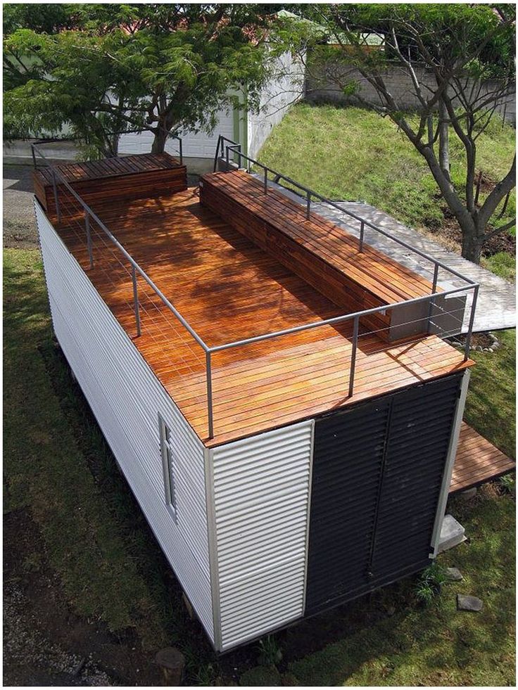 an elevated deck on top of a house in the middle of a field with grass and trees