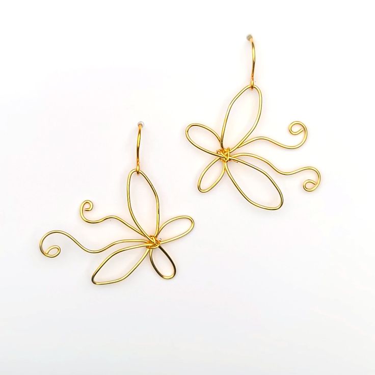 two pairs of gold earrings with swirly designs on the front and back of them