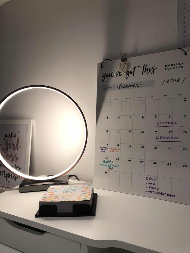 a desk with a mirror and calendar on it next to a lamp that reads you've got this