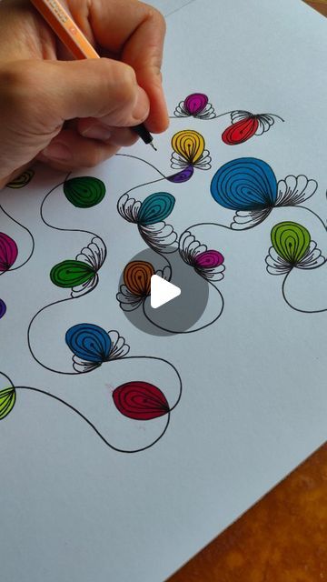 someone is doing something with colored pencils on the paper that has flowers drawn on it