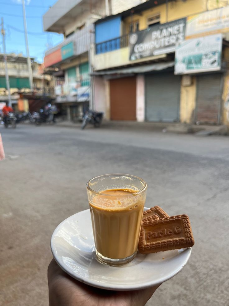 a person holding a plate with a cup of coffee and some waffles on it