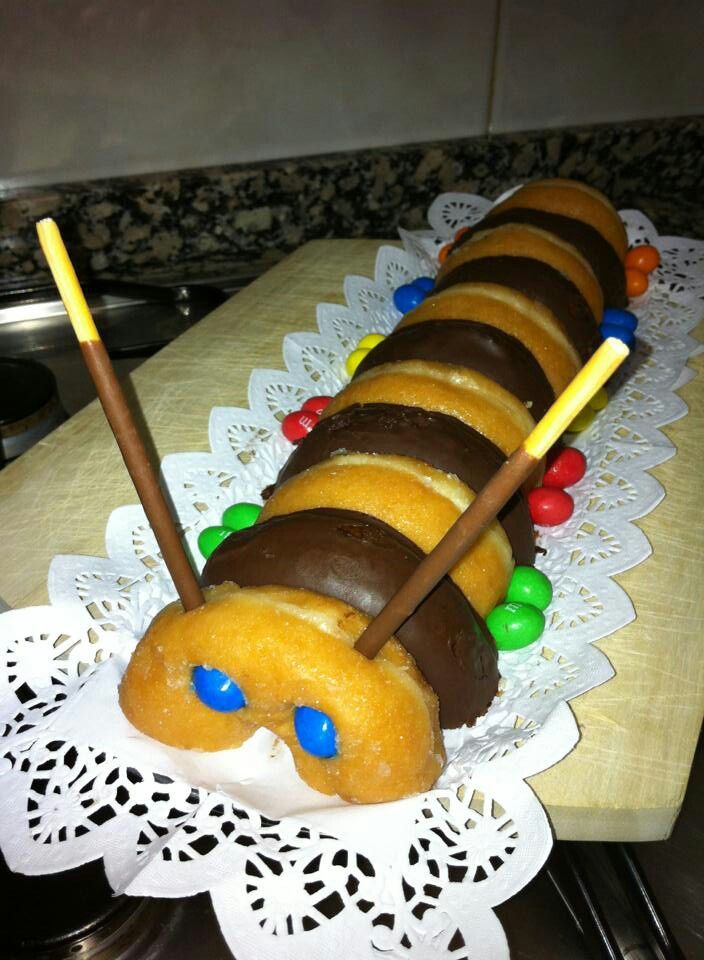 a cake made to look like a caterpillar with candy on it and two sticks sticking out of the top