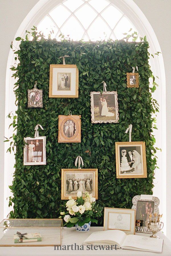 a table topped with pictures and flowers next to a wall covered in green ivys