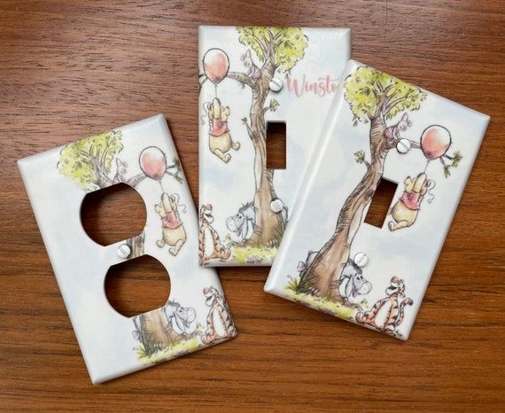 three ceramic outlet covers with winnie the pooh and friends on them sitting on a wooden table