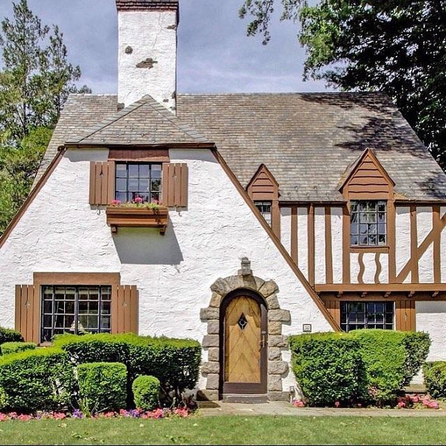 a white house with brown trim and wooden shutters on the front door is shown