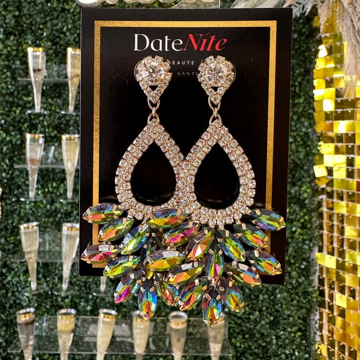 a pair of earrings hanging from the side of a display case with champagne glasses in front of it