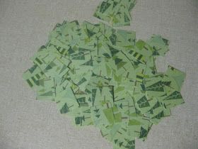 a pile of green pieces of paper sitting on top of a white table next to a wall