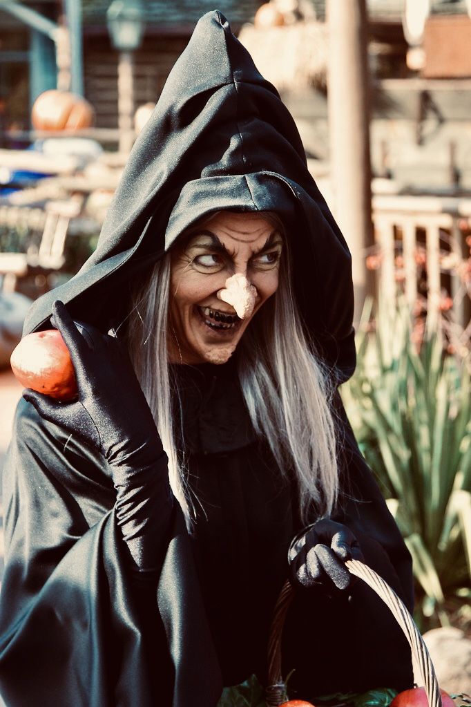 a woman dressed as an evil witch holding a basket