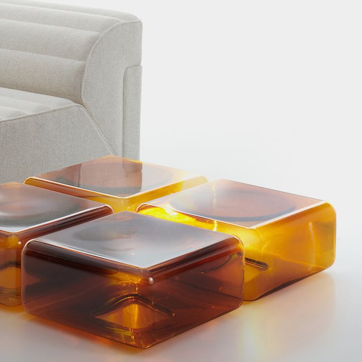 three square glass tables sitting on top of a white table next to a couch and chair