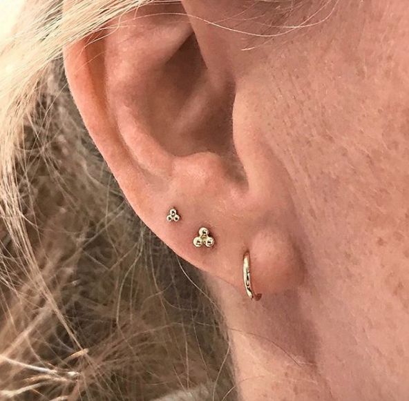 a close up of a person's ear wearing gold earrings