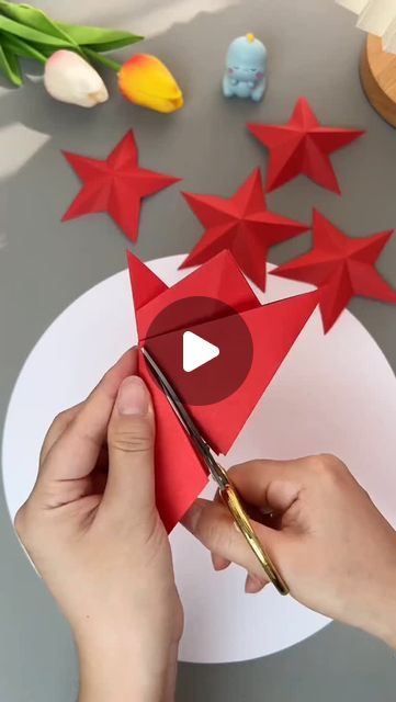 someone is cutting out red paper stars on a table with scissors and other crafting supplies