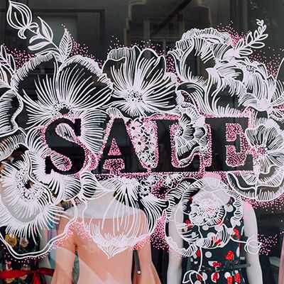 a window display with mannequins dressed in pink and black dresses, flowers and the word sale written on it