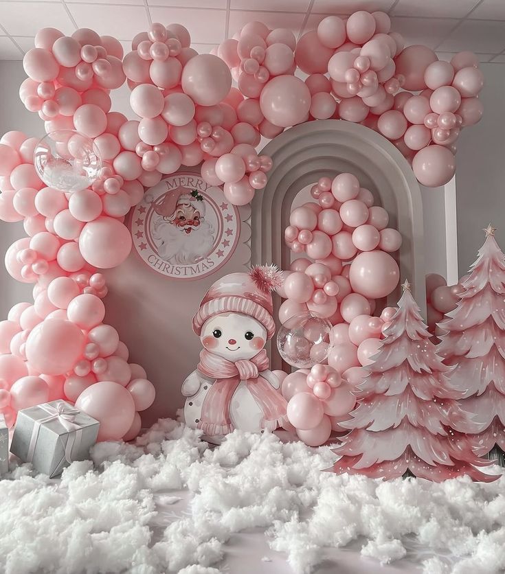 a room filled with pink and white balloons, trees, and snowman in front of a doorway