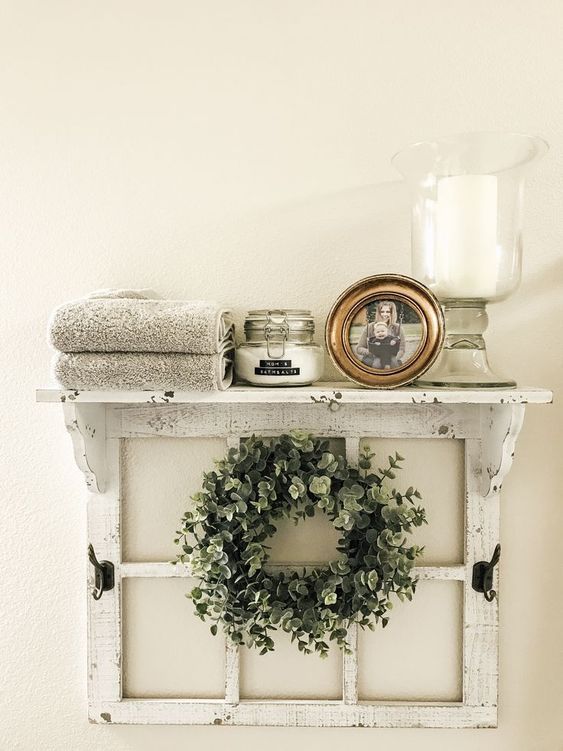 a white shelf with a wreath and candles on it