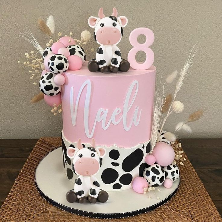 a pink and black birthday cake with cow figurines