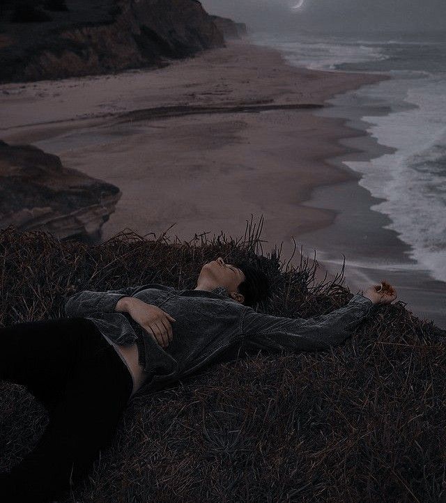 a person laying on the ground next to the ocean