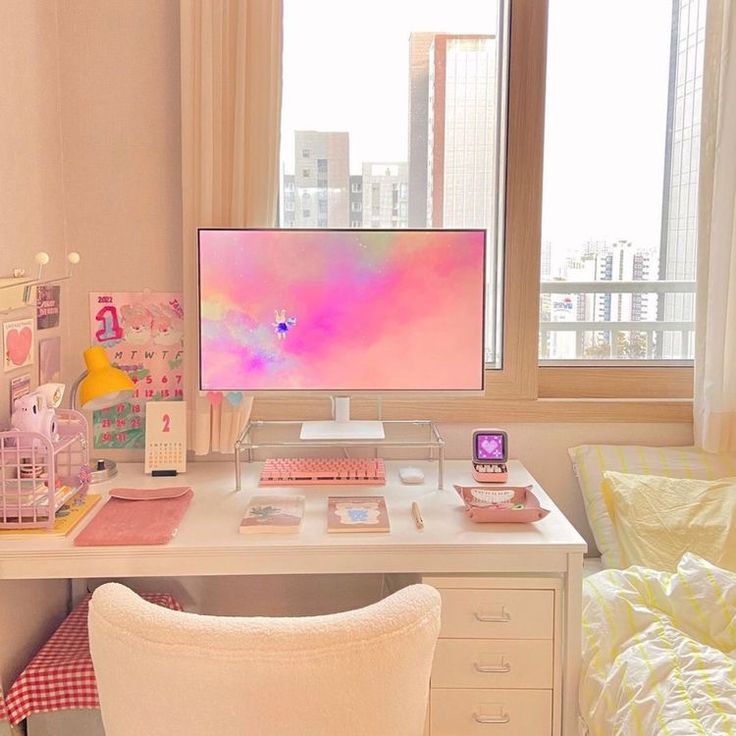 a desk with a computer, phone and other items on it in front of a window