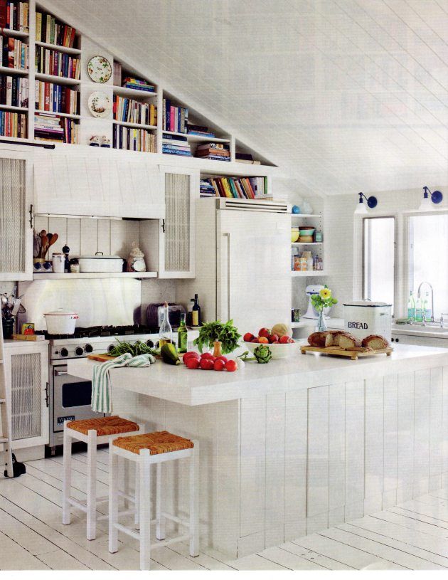 an open kitchen with white cabinets and lots of food on the counter top, along with two stools