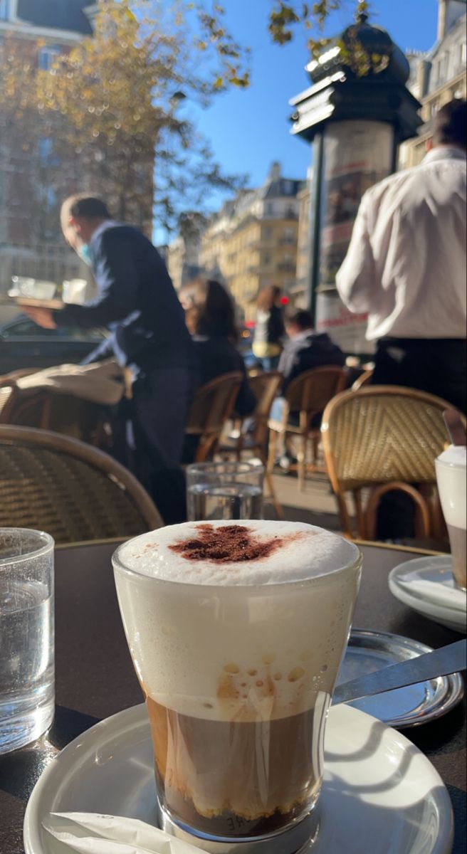 a cappuccino is sitting on a plate at an outdoor cafe