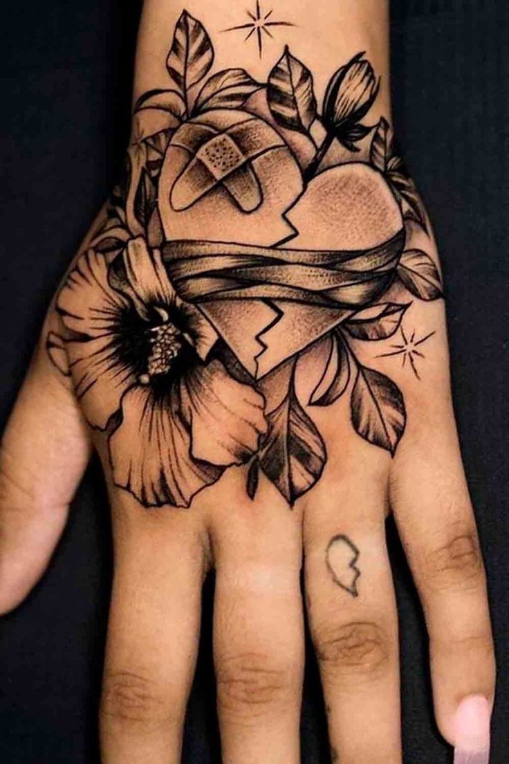 a hand with tattoos on it that has a heart and flowers in the middle of it