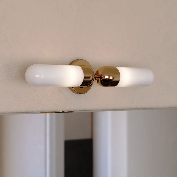 a bathroom light that is on the side of a wall next to a mirror and door