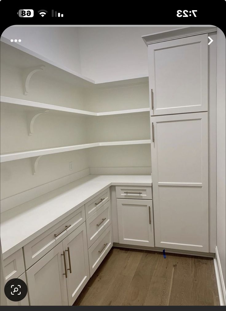 an empty kitchen with white cabinets and wood flooring is seen on the appliance screen