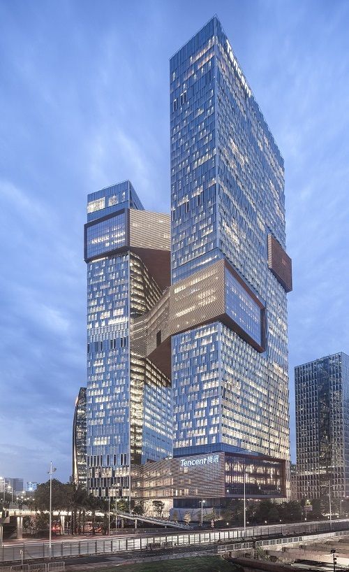 the skyscrapers are lit up at night in front of other tall buildings and water